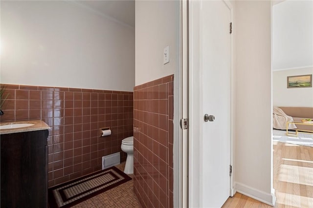 half bathroom featuring visible vents, tile walls, toilet, tile patterned floors, and vanity