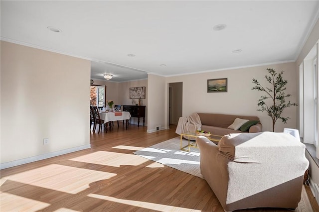 living room with light wood-type flooring, crown molding, and baseboards