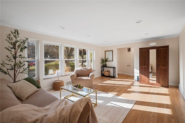 living area with baseboards, light wood-type flooring, and ornamental molding