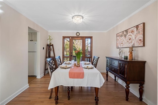 dining space with baseboards, wood finished floors, and crown molding