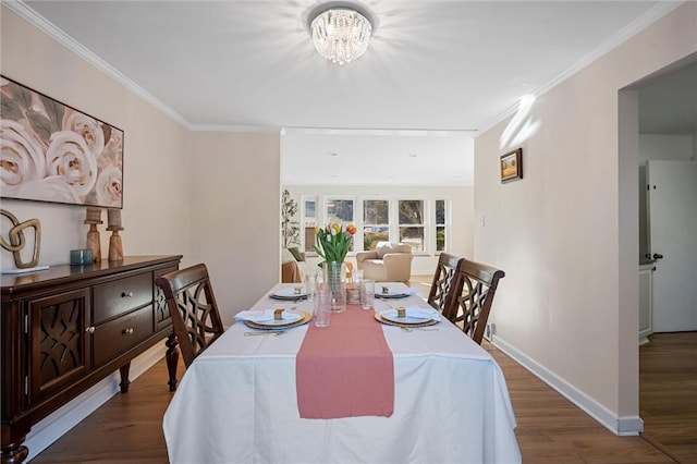 dining room with a notable chandelier, crown molding, baseboards, and wood finished floors