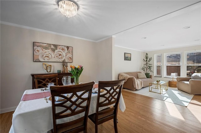 dining room featuring wood finished floors, baseboards, a chandelier, and ornamental molding