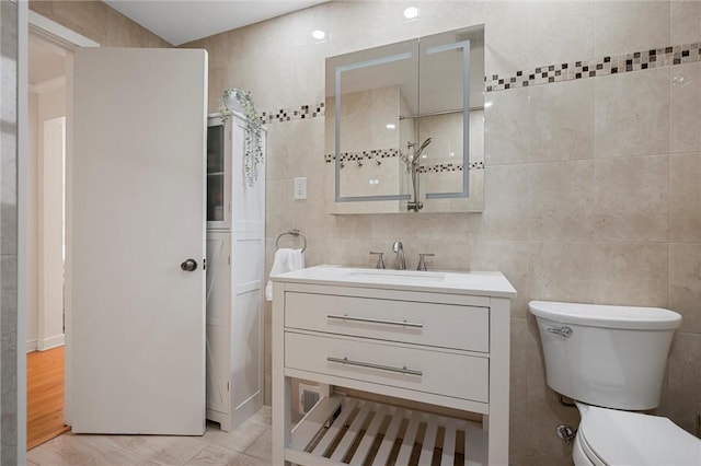 bathroom with vanity, tile walls, and toilet