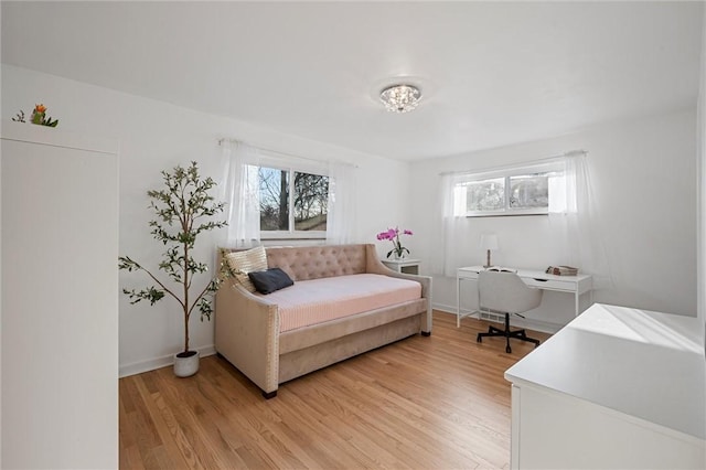 living area featuring light wood-type flooring, baseboards, and a healthy amount of sunlight