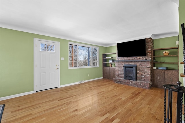 unfurnished living room featuring visible vents, a fireplace, baseboards, and wood finished floors