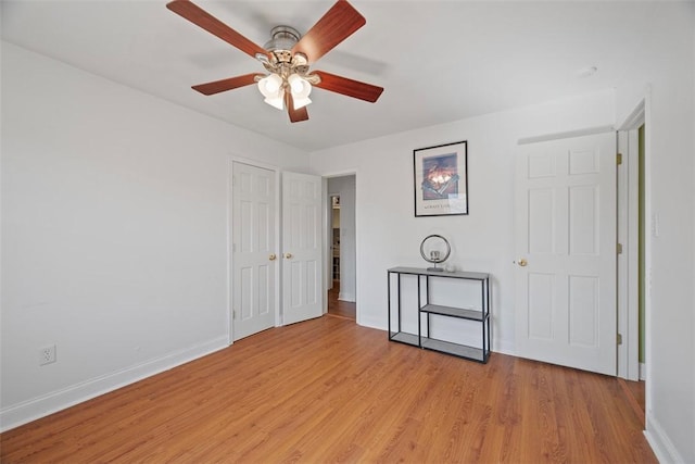 spare room with light wood-style floors, baseboards, and ceiling fan