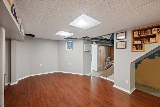 finished below grade area with wood finished floors, baseboards, and a drop ceiling