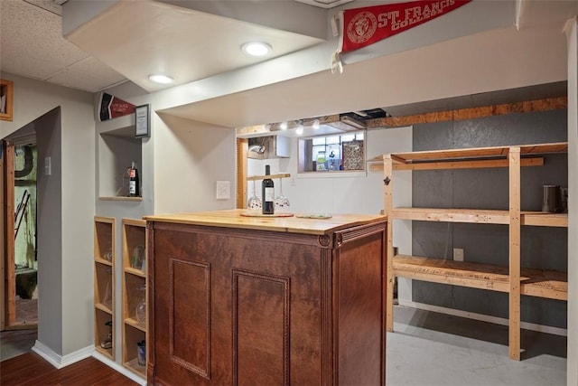 bar featuring wood finished floors, baseboards, and a dry bar