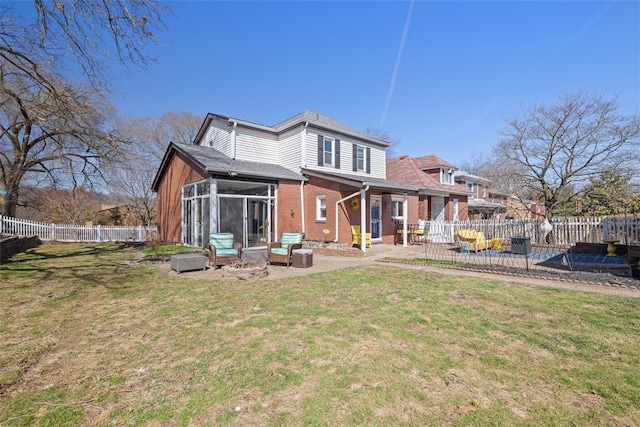 rear view of property with a lawn, brick siding, a sunroom, and fence private yard