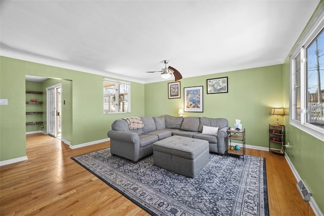 living room featuring visible vents, a healthy amount of sunlight, baseboards, and wood finished floors