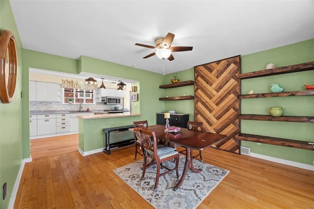 dining room featuring ceiling fan, visible vents, baseboards, and light wood-style flooring