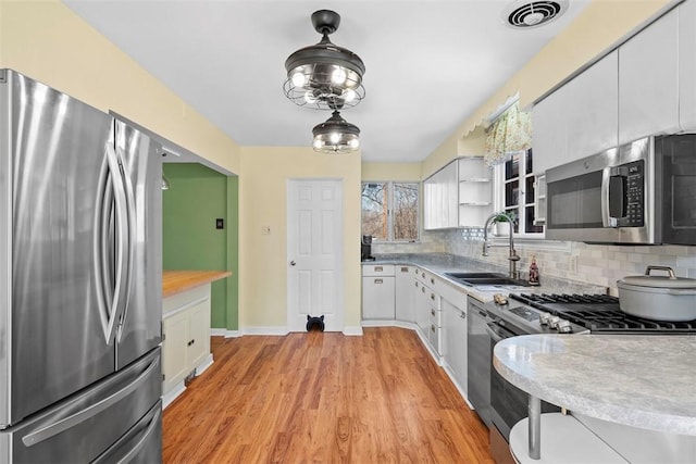 kitchen with visible vents, backsplash, appliances with stainless steel finishes, and a sink