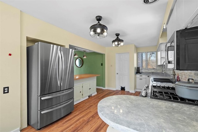 kitchen featuring light wood-style flooring, tasteful backsplash, freestanding refrigerator, white cabinets, and baseboards