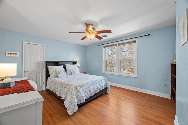 bedroom featuring visible vents, baseboards, wood finished floors, and a ceiling fan