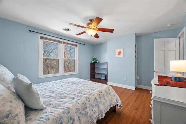 bedroom featuring visible vents, ceiling fan, baseboards, and wood finished floors