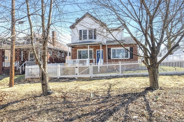 view of front of home featuring a fenced front yard, brick siding, and a porch