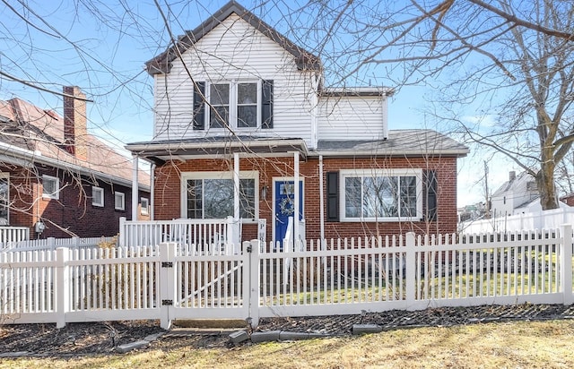 view of front of property featuring a gate, a fenced front yard, a porch, roof with shingles, and brick siding