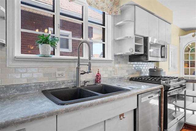 kitchen featuring a sink, open shelves, tasteful backsplash, stainless steel appliances, and white cabinets