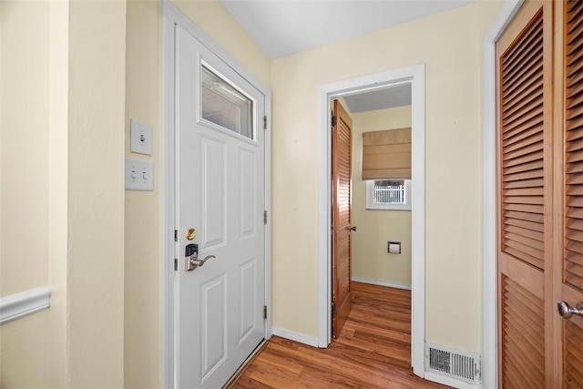 hallway featuring visible vents, baseboards, and light wood finished floors