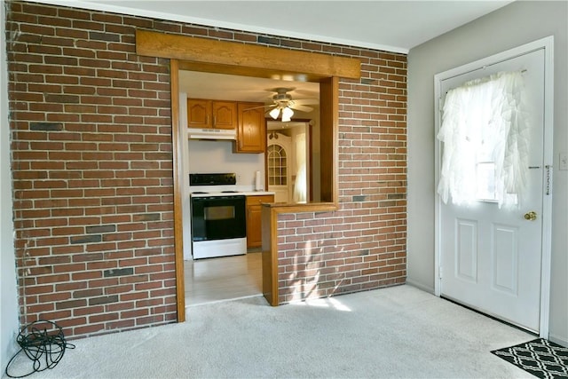 kitchen featuring light carpet, under cabinet range hood, electric range oven, brick wall, and light countertops