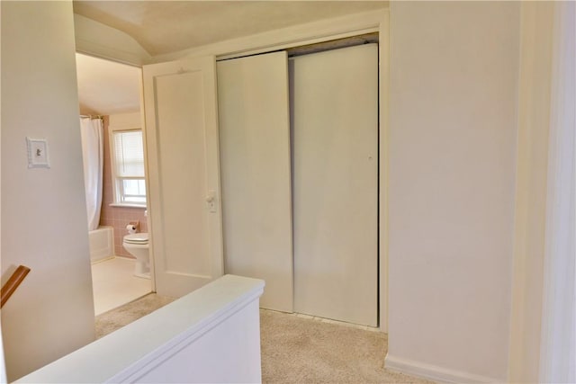 hallway with an upstairs landing, tile walls, and light carpet