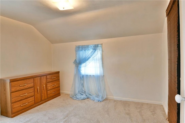 bedroom with lofted ceiling, light colored carpet, and baseboards