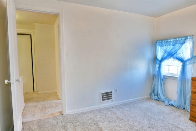 carpeted empty room featuring visible vents and baseboards