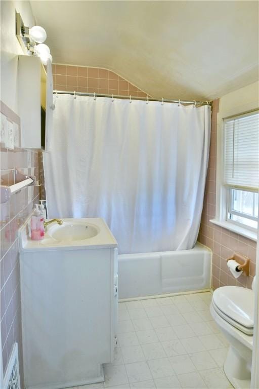 full bath with toilet, vanity, vaulted ceiling, tile walls, and shower / bathtub combination with curtain