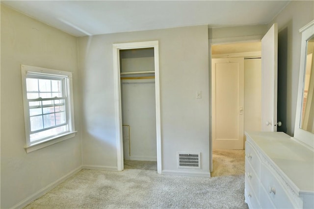 unfurnished bedroom with visible vents, light colored carpet, and a closet