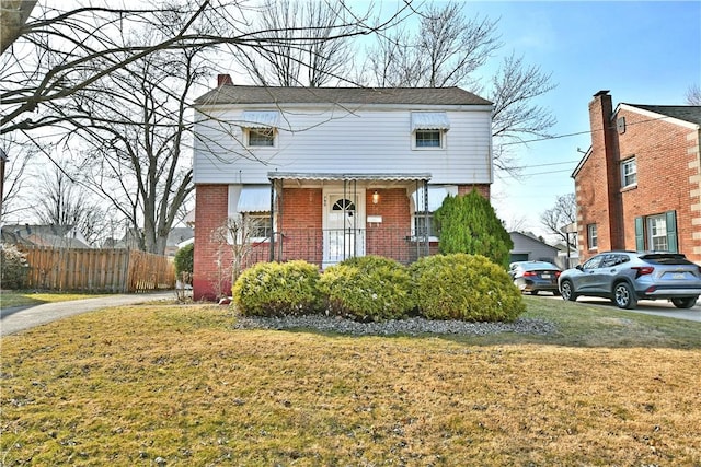 view of front of property with a front lawn, fence, and brick siding