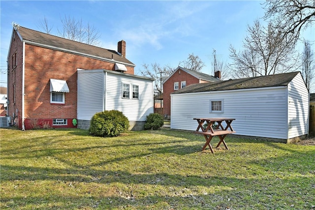 view of side of property featuring a yard, central air condition unit, brick siding, and a chimney