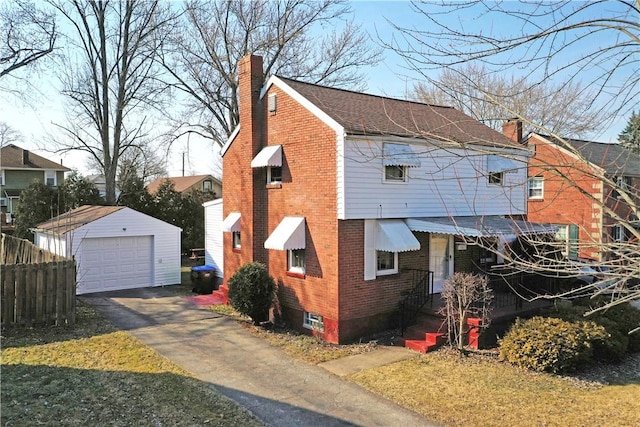 view of property exterior featuring brick siding, a chimney, a detached garage, and an outdoor structure