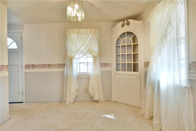 unfurnished dining area with an inviting chandelier and carpet