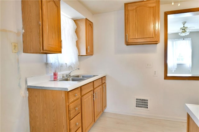 kitchen featuring visible vents, baseboards, light countertops, a ceiling fan, and a sink