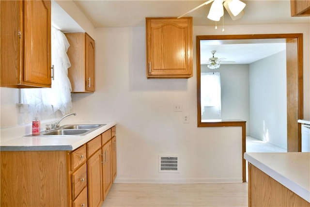 kitchen featuring dishwashing machine, a ceiling fan, visible vents, a sink, and light countertops