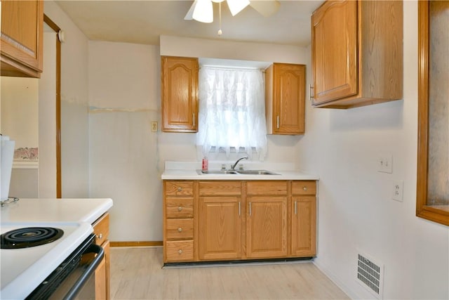 kitchen featuring visible vents, light wood-type flooring, a sink, brown cabinetry, and light countertops