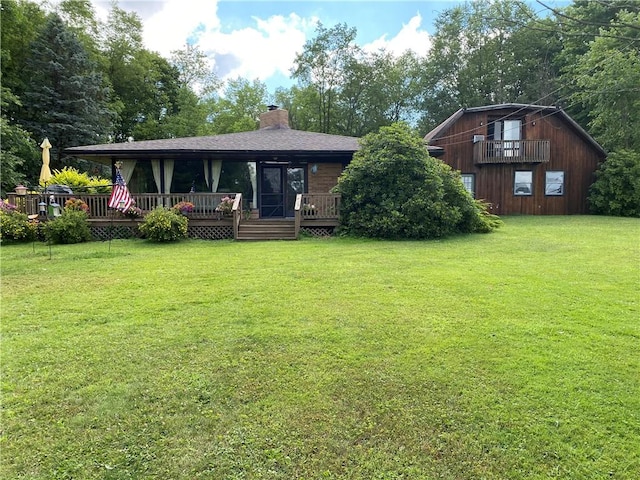 back of house featuring a wooden deck, a chimney, a yard, and a shingled roof