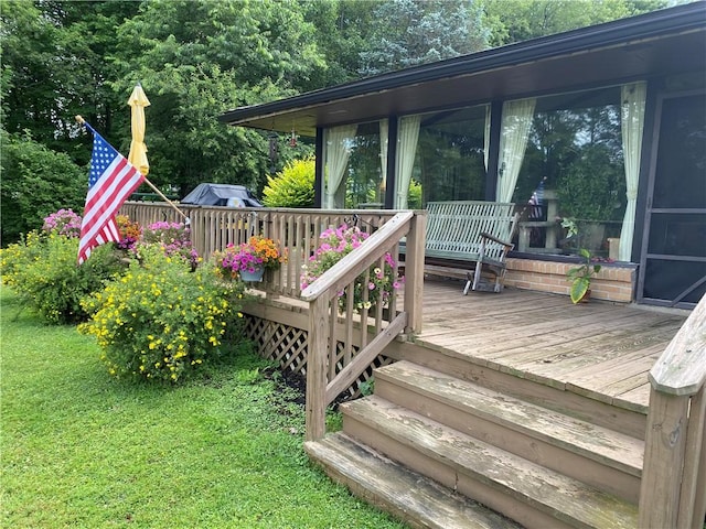 wooden terrace with a lawn and a sunroom