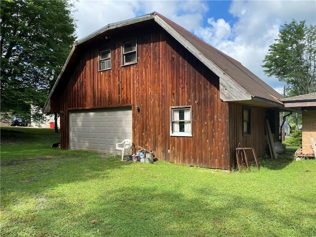 view of property exterior with a garage, an outbuilding, a lawn, and driveway