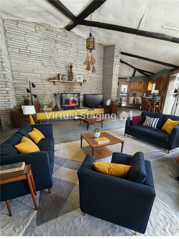 living area featuring a fireplace, vaulted ceiling with beams, and concrete floors