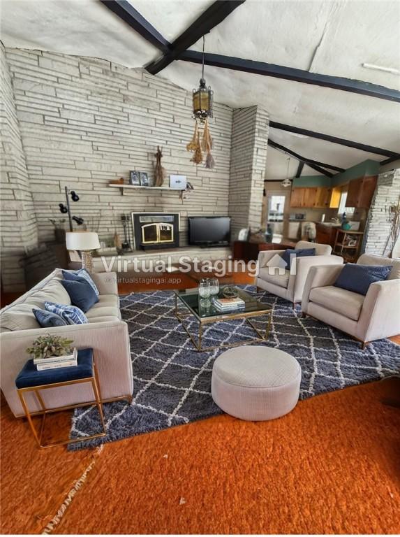 living room with lofted ceiling with beams, a large fireplace, and wood finished floors