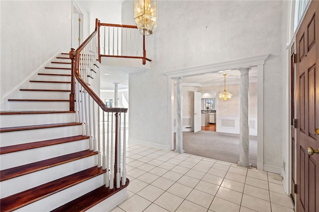 foyer entrance featuring stairway, a towering ceiling, and decorative columns