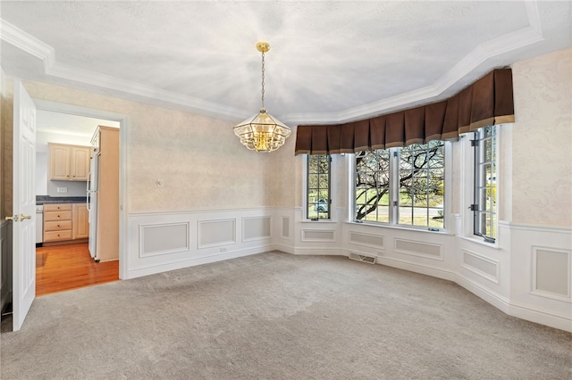 unfurnished dining area featuring visible vents, a chandelier, a wainscoted wall, ornamental molding, and light carpet