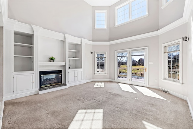 unfurnished living room with a wealth of natural light, baseboards, a glass covered fireplace, and carpet flooring