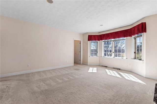 spare room with visible vents, baseboards, light colored carpet, and a textured ceiling