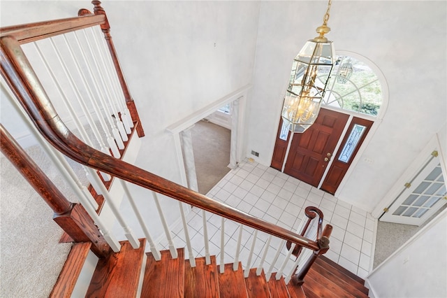 foyer with visible vents, stairway, a high ceiling, an inviting chandelier, and wood finished floors