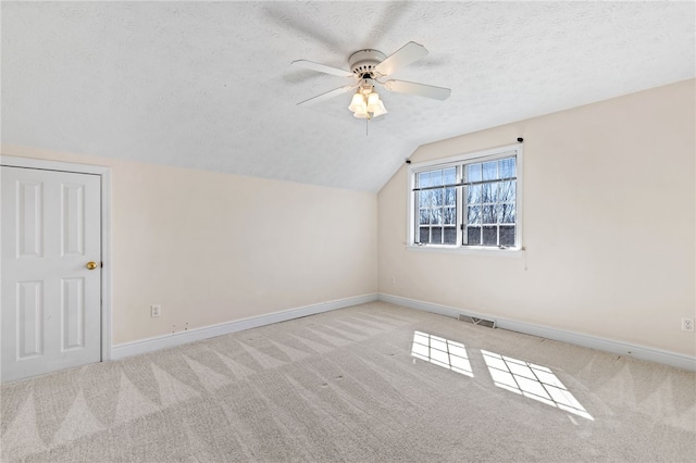 bonus room featuring baseboards, carpet floors, a textured ceiling, and lofted ceiling