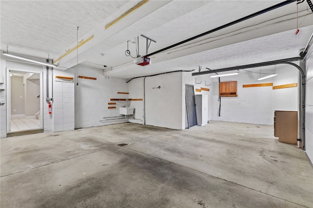 garage with a garage door opener and concrete block wall