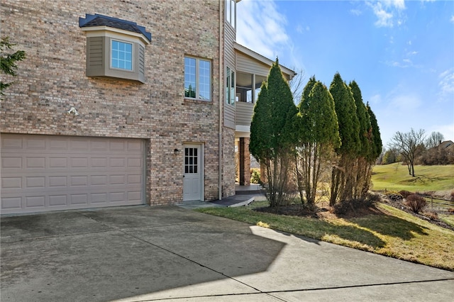 view of side of home featuring an attached garage, brick siding, and driveway