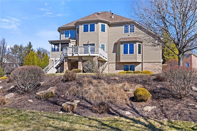 rear view of property featuring stairway, a wooden deck, and a sunroom